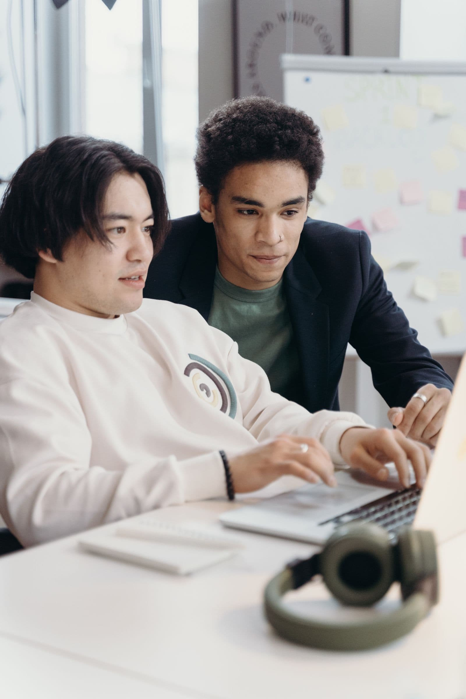 Two colleagues concentrating on a laptop together at their desk
