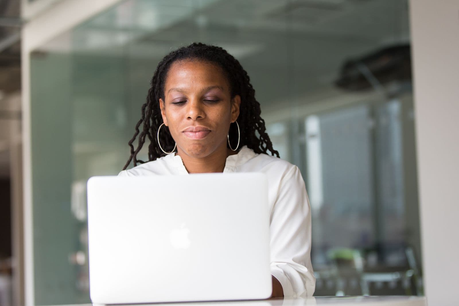 Woman in a white shirt concentrating on her laptop at a desk